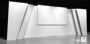 Stage backdrops for events with triple depth, symmetrical sides with two angled pieces on each side and a front projection screen in the centre.
