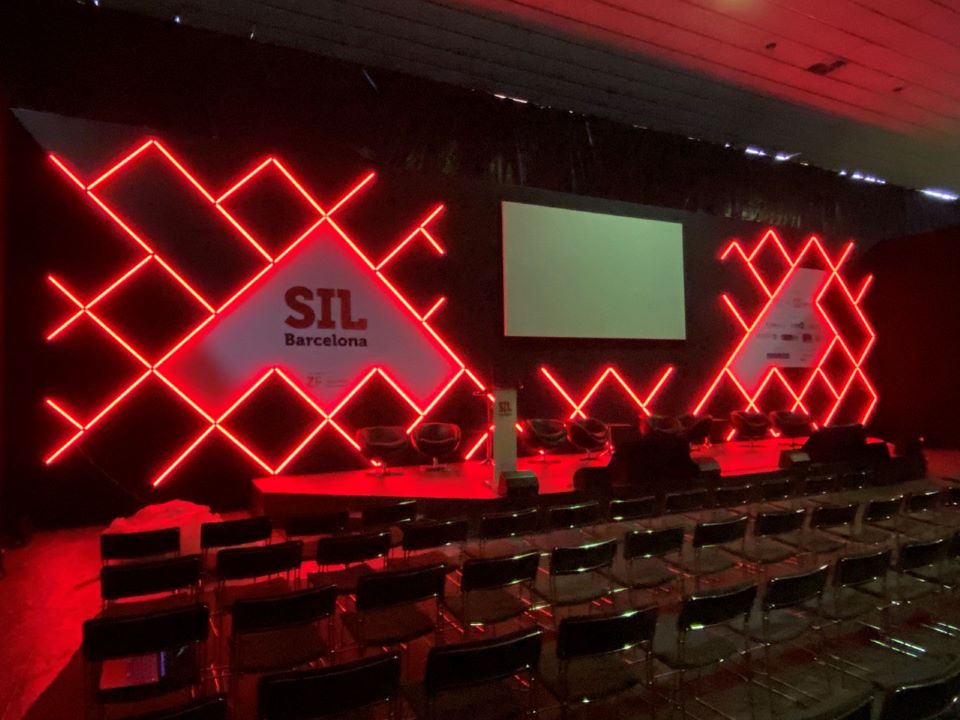 Salle de conférence avec fond de scène avec écran de projection frontale pour SIL 2022