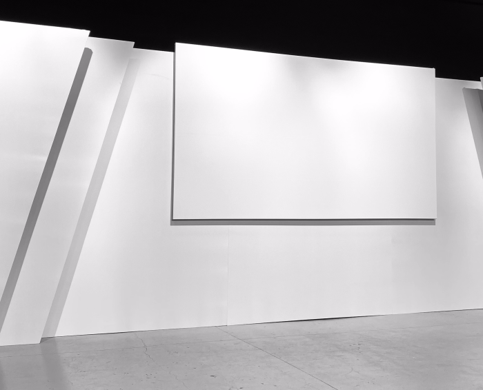 Bühnenhintergrund mit dreifacher Tiefe, symmetrischen Seiten mit zwei Teilen mit gewinkelten Abschlüssen auf jeder Seite und einer mittig positionierten Frontprojektionsleinwand.